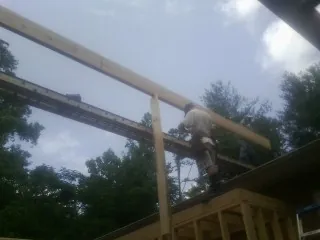 Carpenter setting a ridge beam over a new addition frame — Ice Dam Removal by Roofing Brothers in College Springs