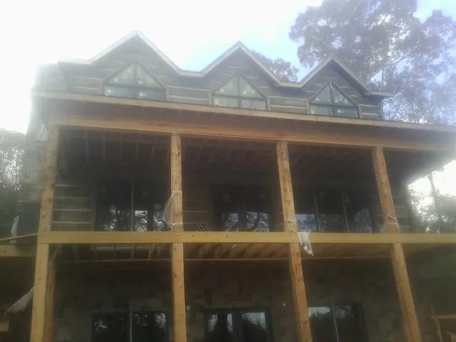 Dormers and porch framing on a large log home under construction — Roof Coating work by our crew in College Springs