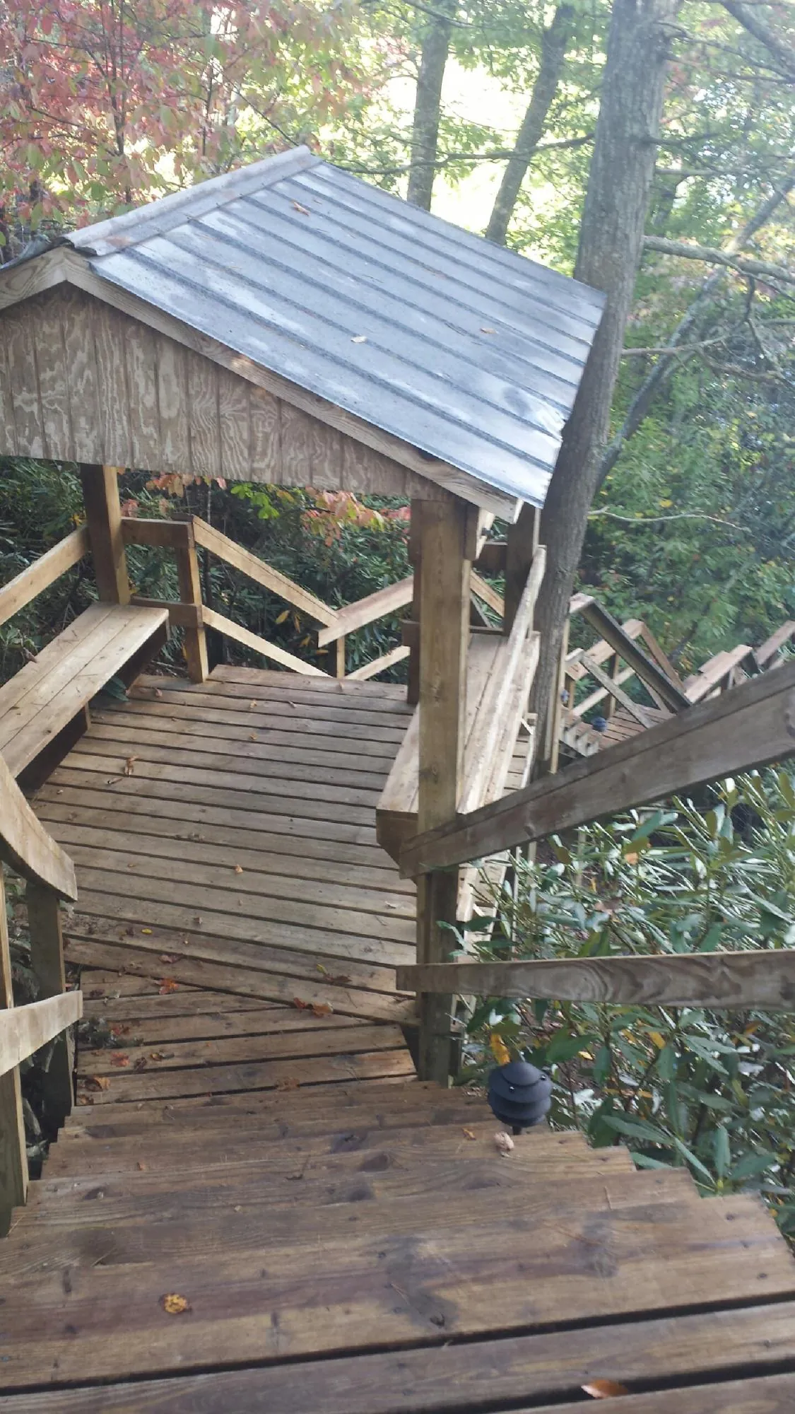 Metal roofed shelter over wooden steps on a wooded walkway — Skylight Repair & Installation work by our crew in College Springs
