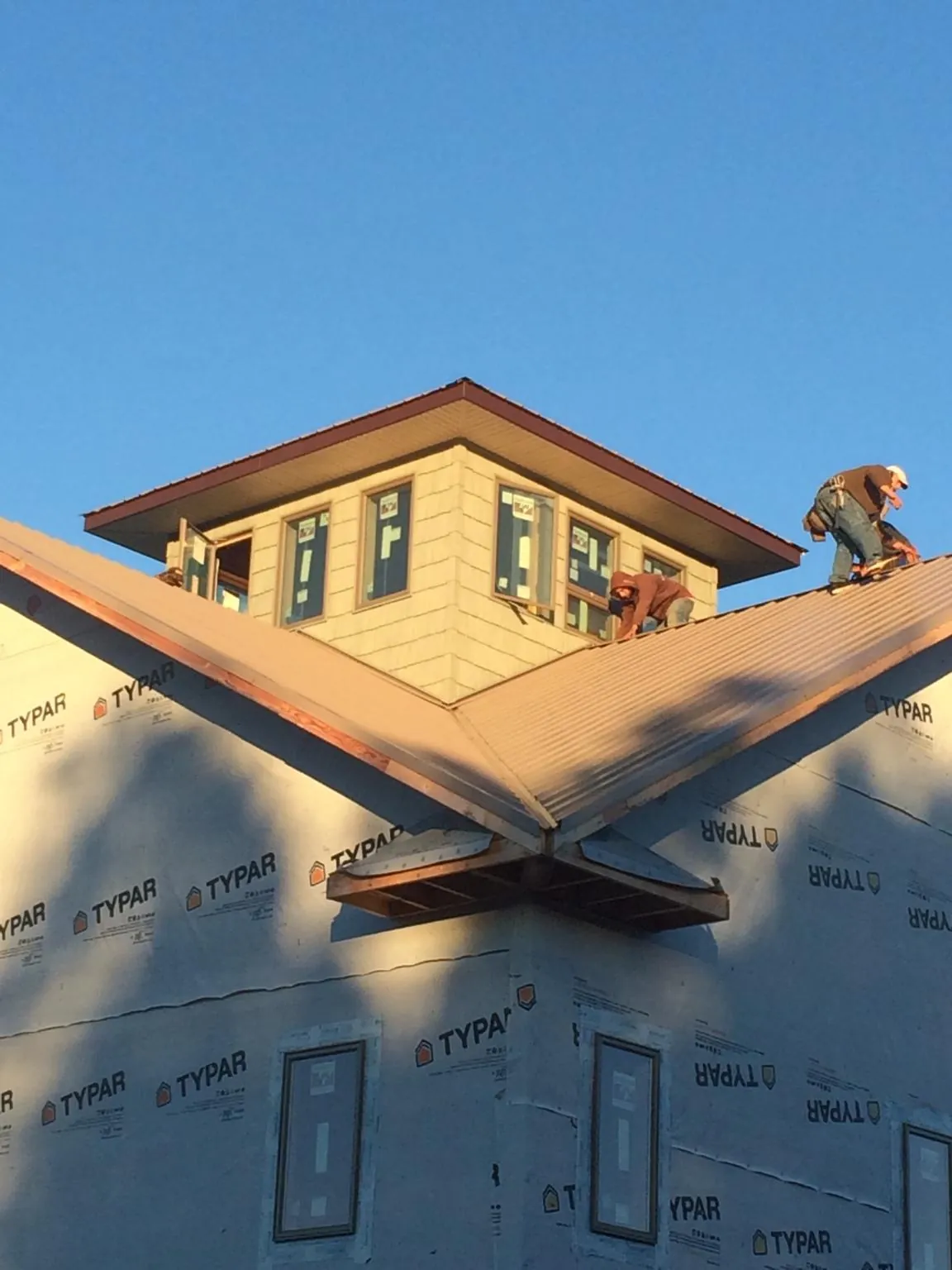 Roofers working around a rooftop cupola on a new metal roof at sunset — Roof Waterproofing in College Springs by Roofing Brothers